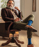 Man wears the Juzo Adventure in blueberry and sits at his desk