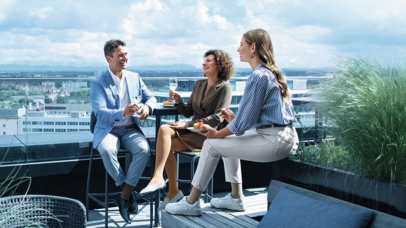 Venner sidder ved et bord i en tagterrassebar og har kompressionsbandager på