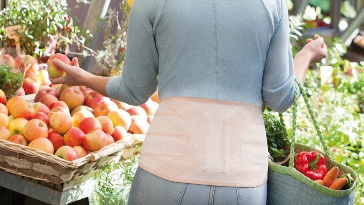 Femme au supermarché avec orthèse dorsale