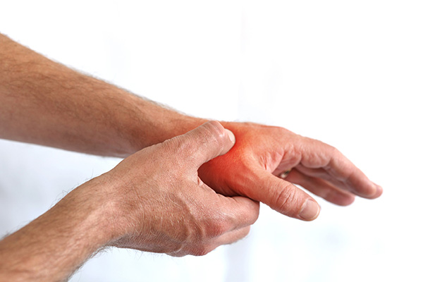 Eine Person hält sich ihre Hand wegen Schmerzen im Daumen fest