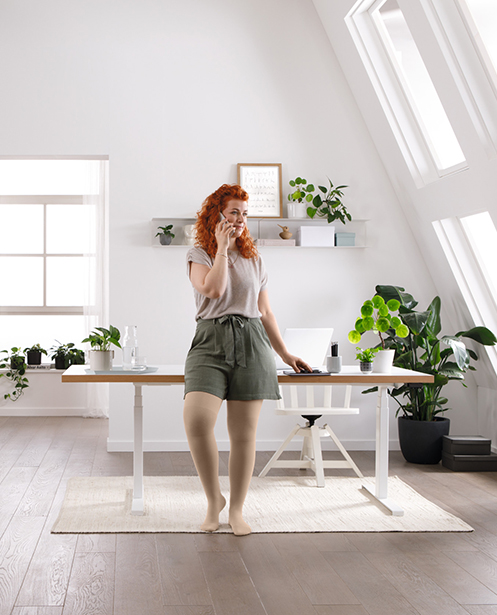A woman is standing at her desk, talking on the phone