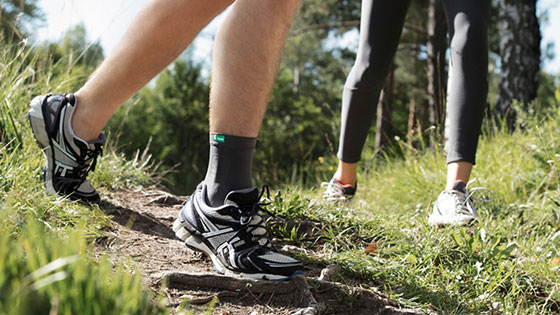 Jemand läuft über einen Feldweg und trägt dabei eine Sprunggelenkbandage